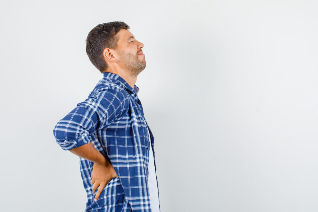 Young man in shirt suffering from backache and looking painful.